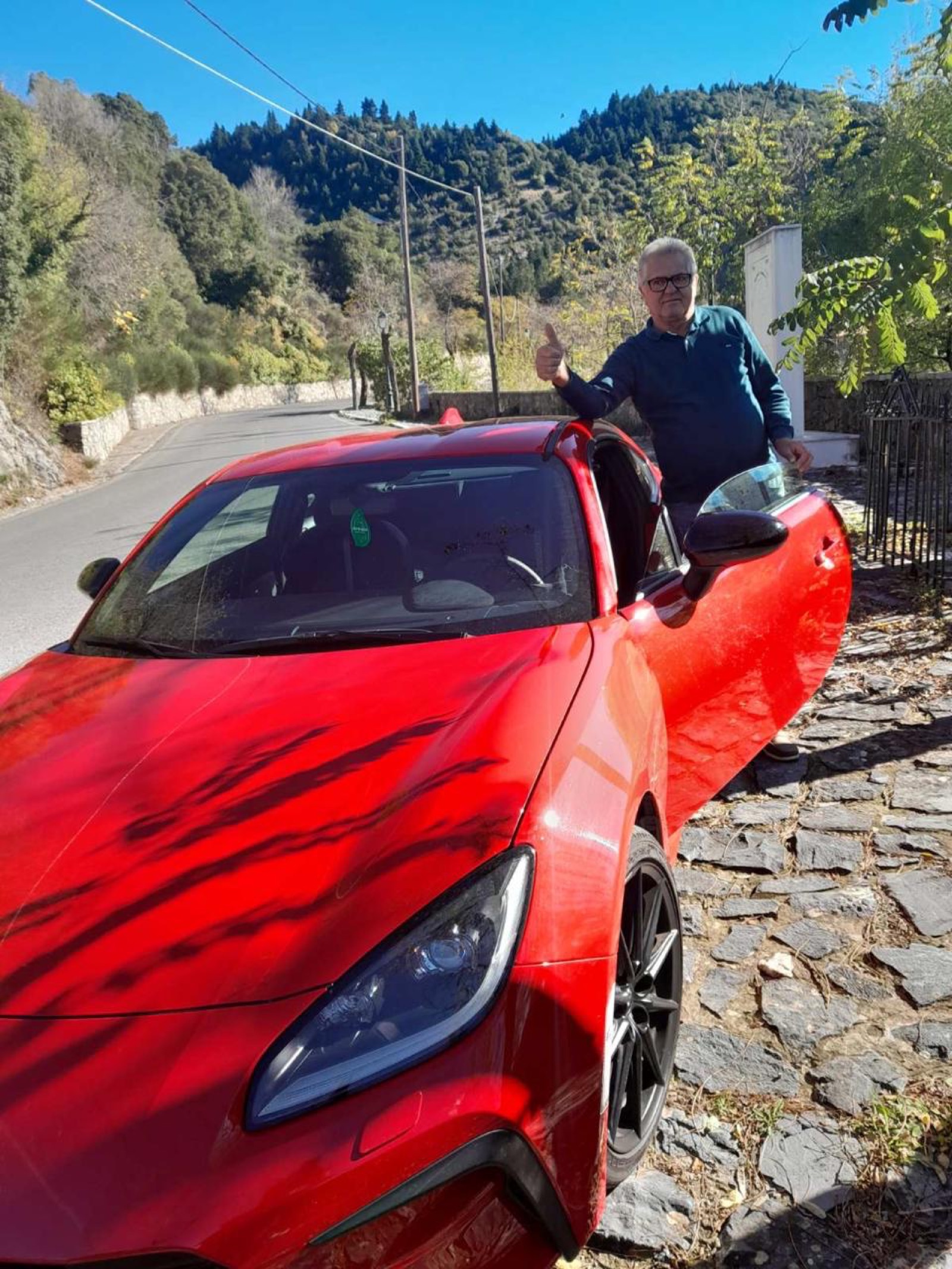 Dad giving thumbs up next to the GR86 in a mountain village