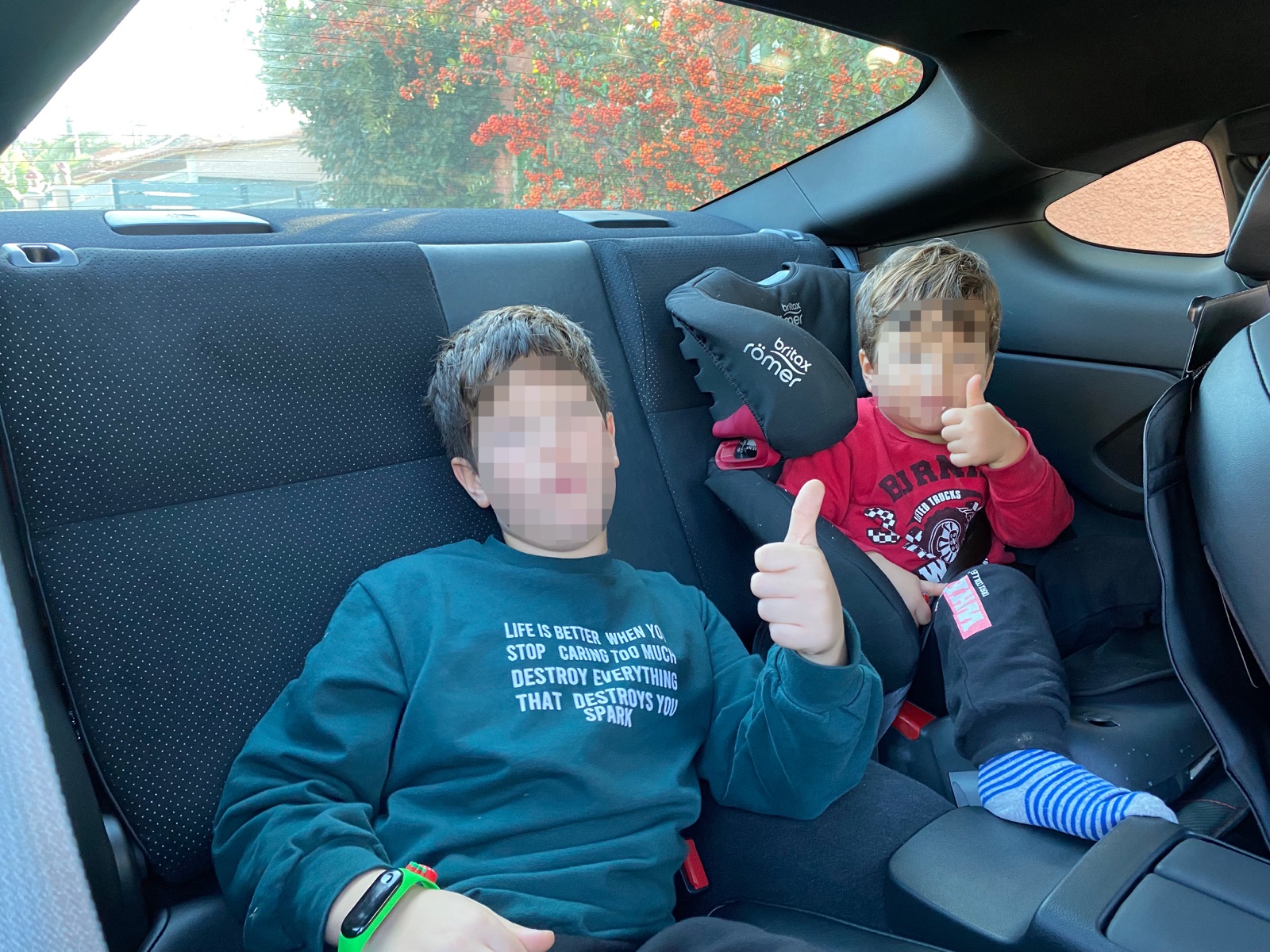 Kids in the back seat giving thumbs up